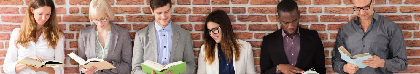 People with books against a brick wall
