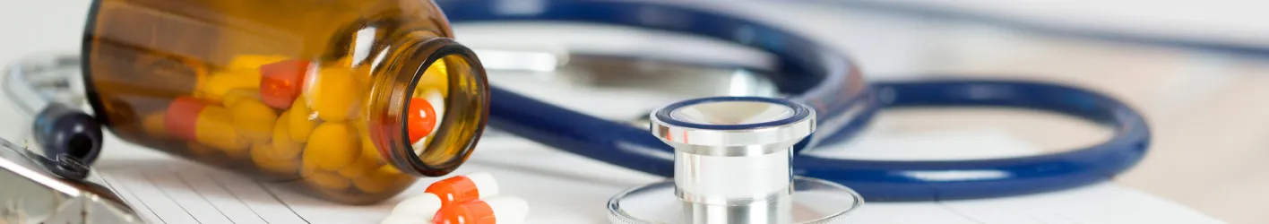 tipped bottle of medication next to a stethoscope 