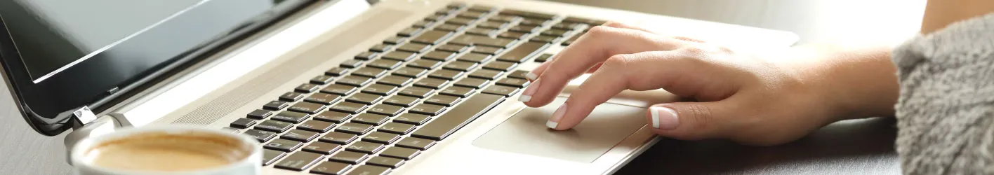 Someone working on a laptop with a cup of coffee to the side