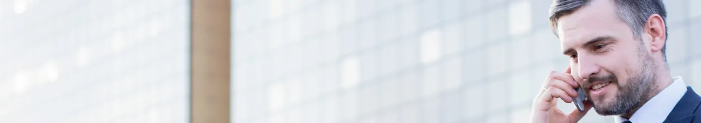 Business Man talking on phone with skyscraper office buildings in the background.