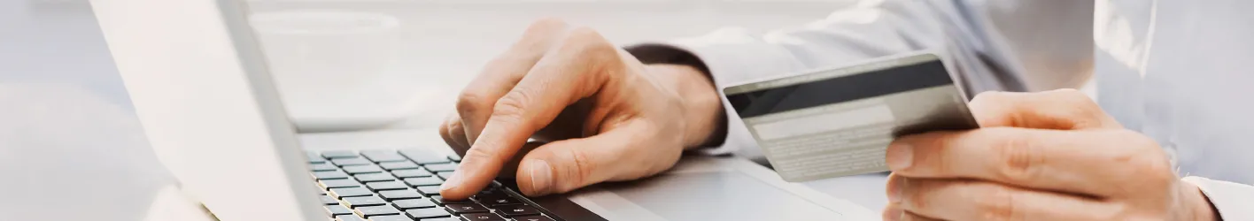Person looking at credit card an inputting the information into his laptop
