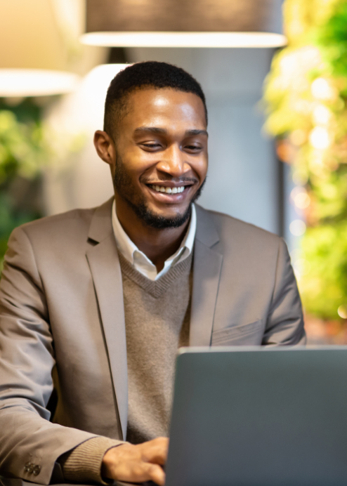Worker in white shirt, sweater, and jacket at a laptop