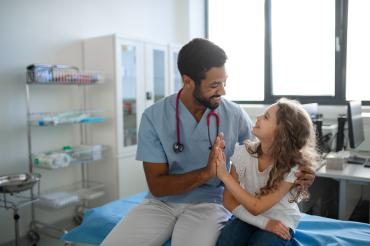 Doctor sitting with child giving a high five